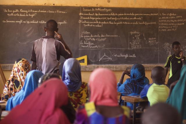 Enfants avec professeur au tableau dans une école