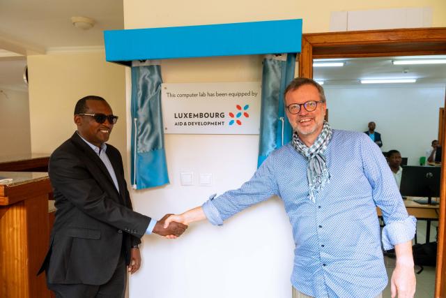 Two men shaking hands in front of a sign