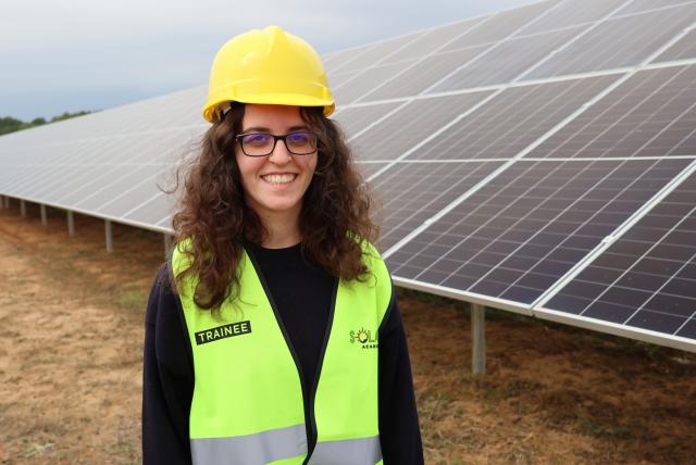 Student posing in front of solar panels