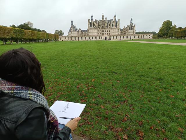 Liza drawing a castle in Blois, France sitting on the grass