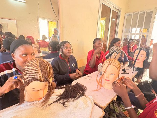 Apprenantes en soins esthétiques participant à un cours de tressage sur des têtes à coiffer