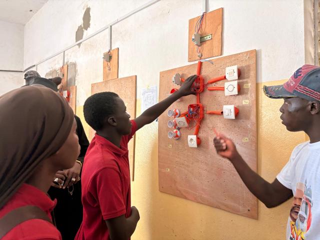 Apprenants rassembler autour d'un panneau destiné l'apprentissage de l'électricité