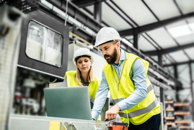 A man and a woman looking at a computer in a factory