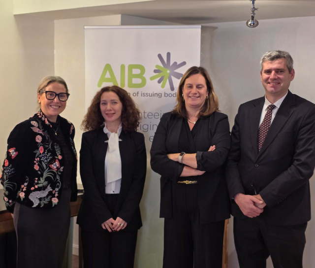 Four people standing in front of a AIB roll-up