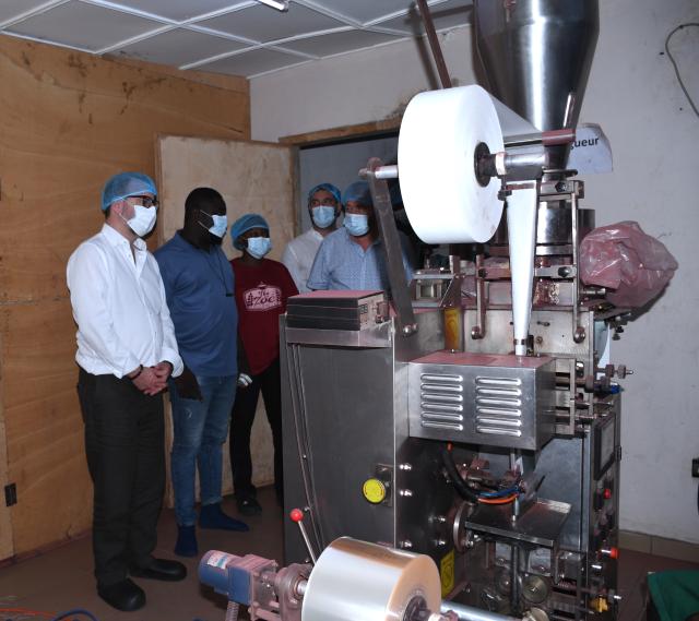 Hommes portant des masques et des charlottes regroupés autour d'une machine