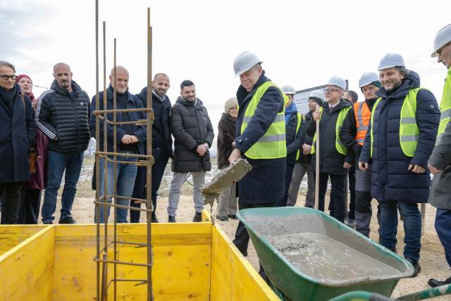 Ambassador laying cement mix on the foundations of the new building