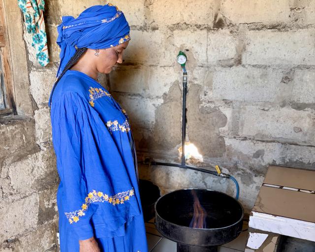 Femme devant son système de cuisson au biogaz. 